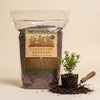 OrganiLock Landscape Refresh bag beside a young shrub and a garden trowel